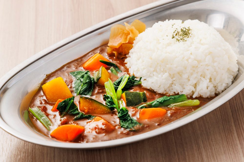 季節の野菜カレー。銀の皿に、かぼちゃ、にんじん、小松菜の入ったカレーとごはん